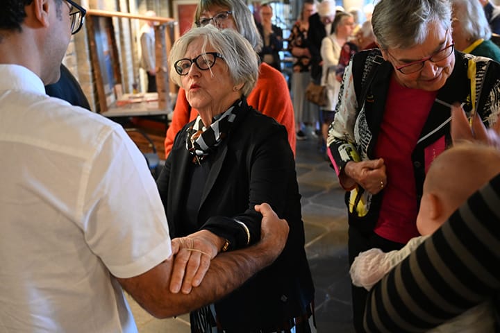 Vrouw krijgt een troostende handdruk van een man, met anderen om haar heen in een warme, steunende sfeer.